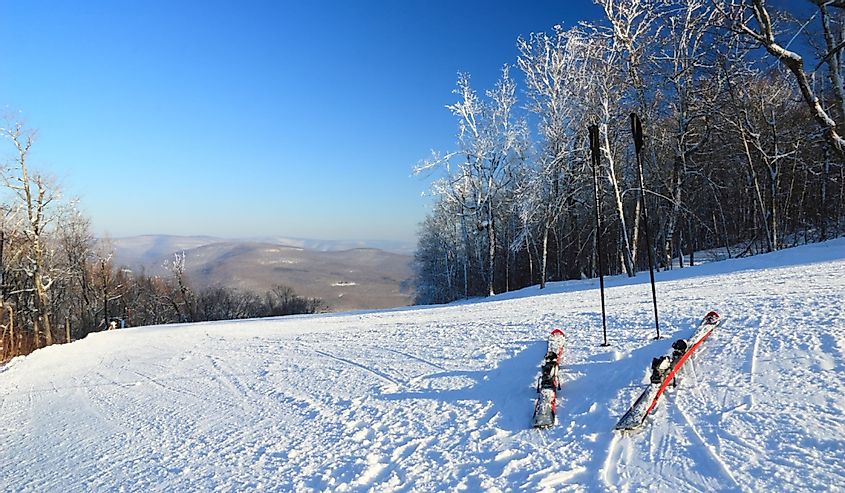 Snow clad skis and poles at the top of a ski trail at Belleayre Mountain Ski Resort in the Catskills Mountains of New York