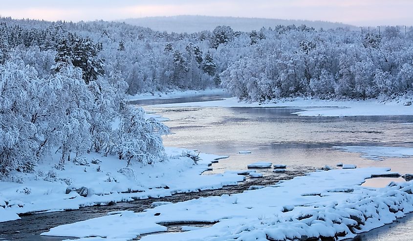 Cold winter sunset at the river Glomma located in the central part of Norway, trees covered with frost and snow.