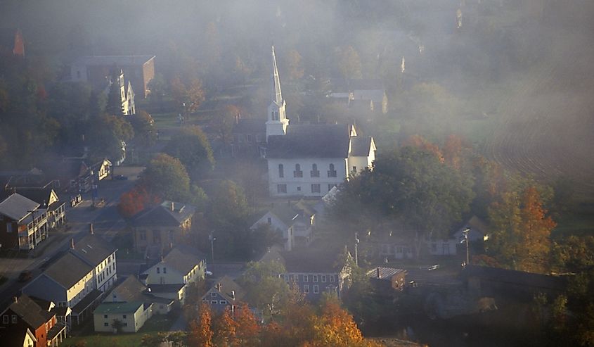 Aerial view of Waitsfield, VT in fog with church steeple on Scenic Route 100 in Autumn