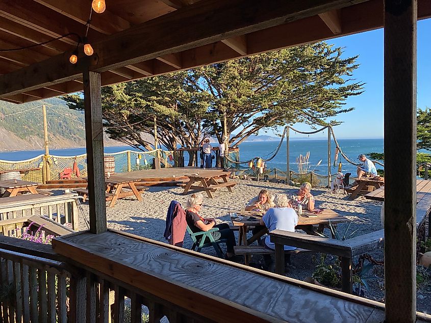 A few picnic tables in the sand atop a bohemian clifftop, oceanview bar