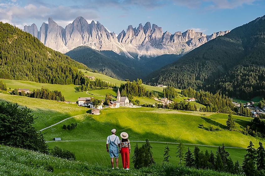 A couple viewing the landscape of the Santa Maddalena village in Dolomites, Italy