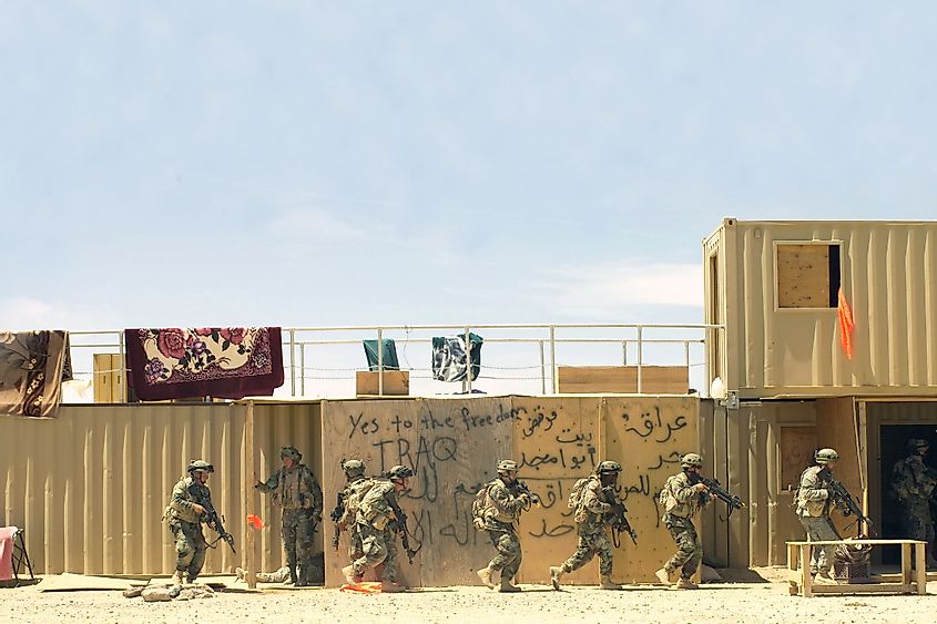 Soldiers move forward to search a building during training at the National Training Center