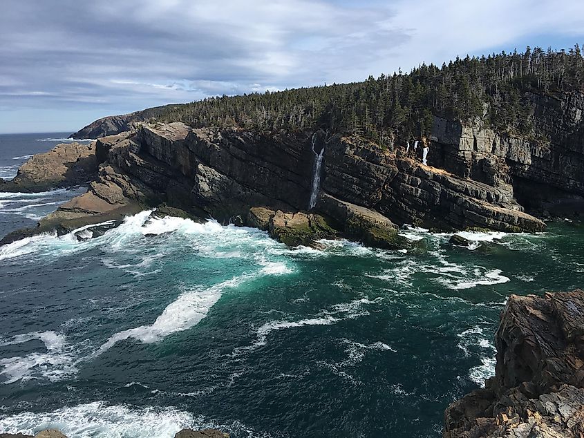 Thin waterfalls coming off of sheer cliffs into the ocean