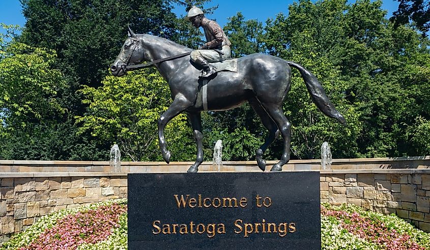 "Welcome To Saratoga Springs" statue of jockey riding horse.