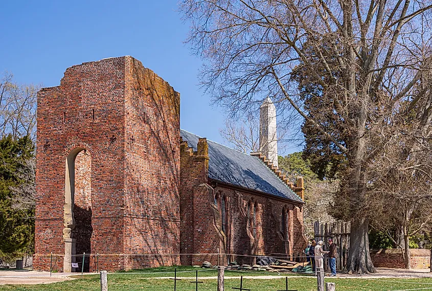 Red brick ruin of original church tower with nave reconstructed  in 20th century against blue sky in Jamestown, Virginia