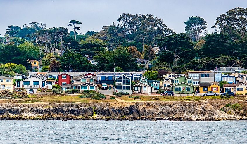 Houses in Pacific Grove, California (in Monterey County) overlook the rocky coastline, as viewed from a passing boat.