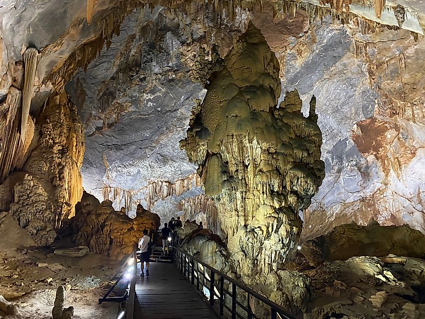 A bulbous stalactite stands in a massive cave chamber.