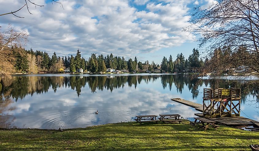 Homes, trees and sky are reflected in the water of Mirror Lake in Federal Way, Washington.