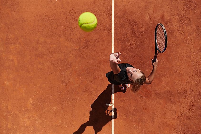 Top view of a professional female tennis player serves the tennis ball on the court