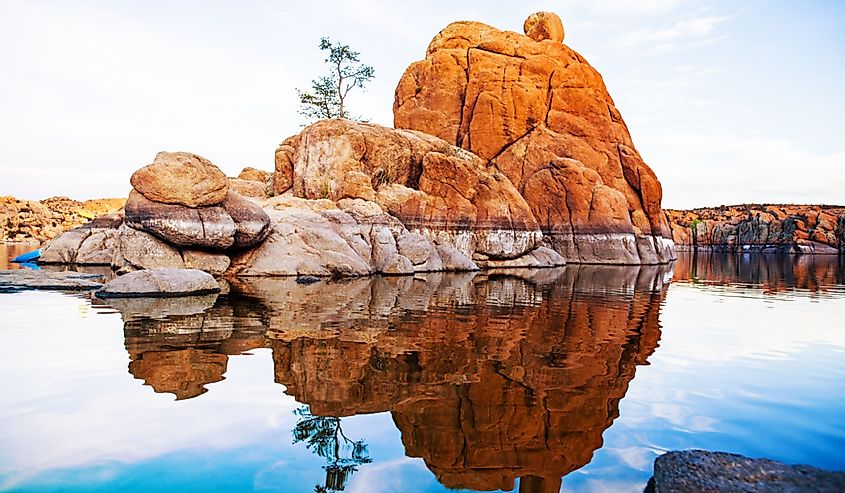 Large red rock formation with one tree in the middle of Watson Lake in Prescott, AZ, USA