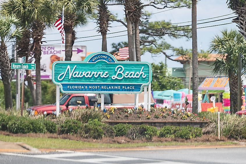 The Welcome to Navarre Beach city sign by a road in Navarre Florida. 