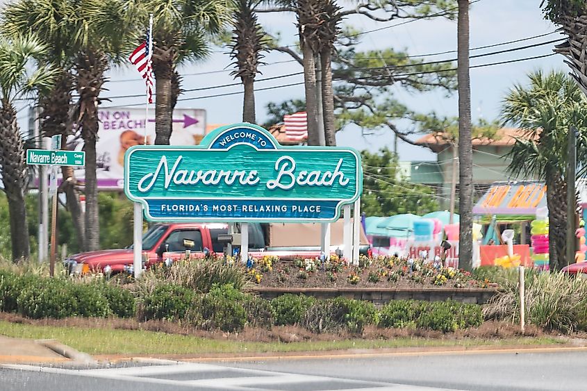 The Welcome to Navarre Beach city sign by a road in Navarre Florida.
