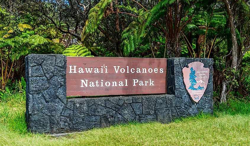 The Sign for Hawaii Volcanoes National Park in front of a vibrant green meadow.