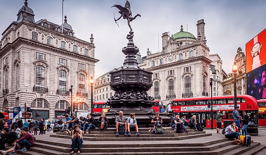 The historic architecture of London in the United Kingdom at sunset showcasing Piccadilly Circus with lots of locals and tourists passing by