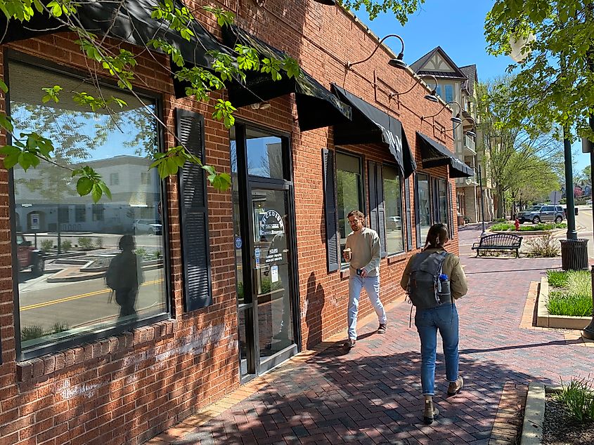 Pedestrians strolling along a brick-lined sidewalk past a small town coffeeshop