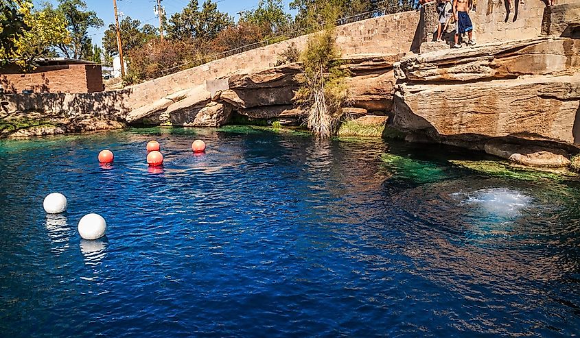 People standing on rocks and orange balls on the water in Blue Hole on Route 66