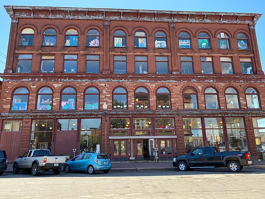 A large, three-story red brick building with colorul art work in the windows.