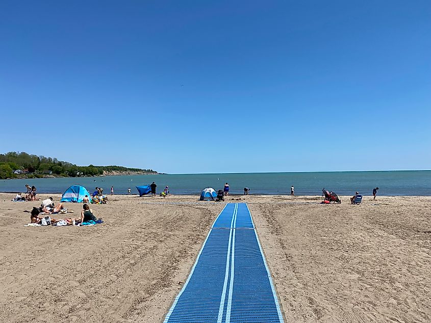 A blue mobility mat rolls out onto a small cove beach.