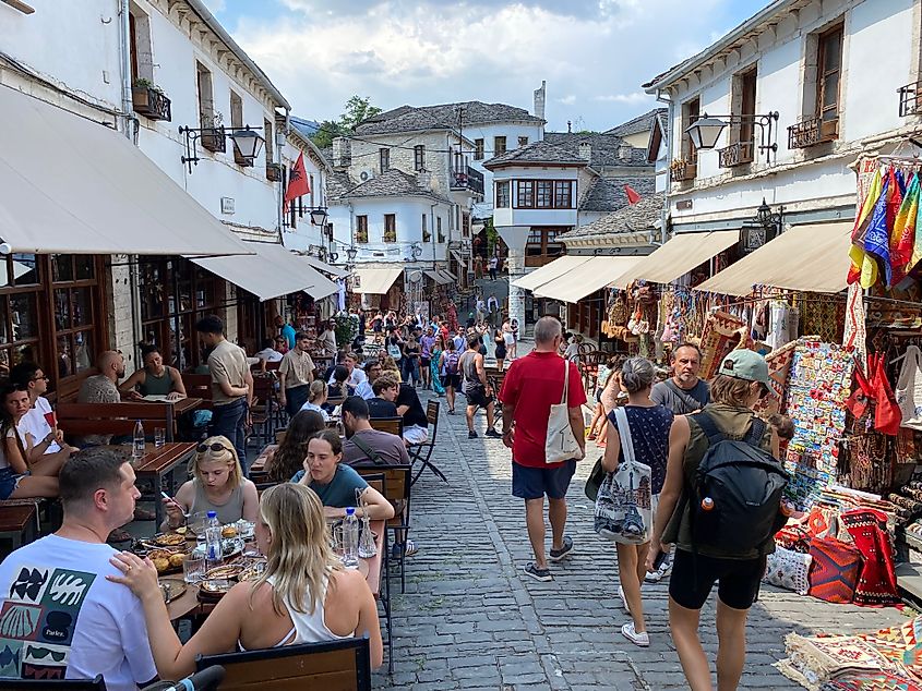 A cobblestone old town full of shoppers and people dining at streetside tables.