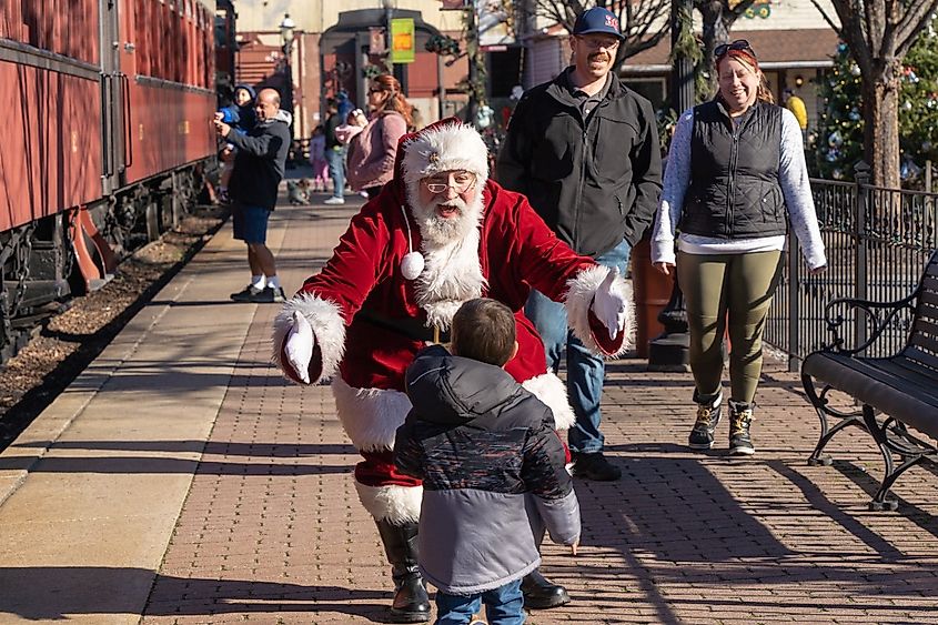 Santa Claus greets small child at Strasburg Railroad Christmas train ride experience.
