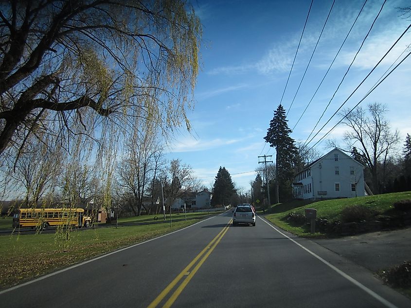 Tree-lined River Road in Niskayuna, New York, with a sidewalk running alongside and homes set back from the road