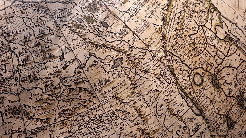 Antique globe showing Central Asia and China with illustrated camels and mountains, labelled with old-world Silk Road trade routes