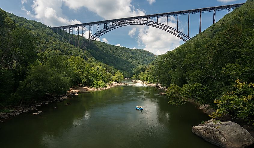 Rafters float towards the rapids under the high arched New River Gorge bridge in West Virginia