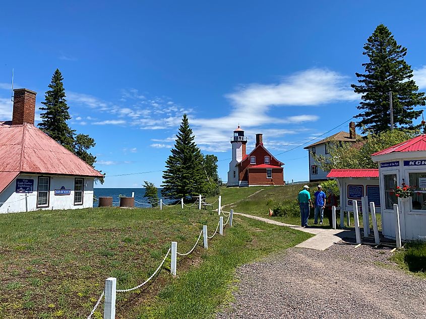 Two older men having a chat at the opening of a historic lakeside lighthouse facility. 