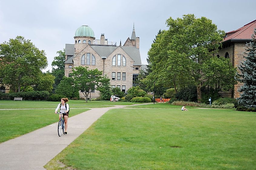 An Oberlin student rides her bicycle through the main quad in front of Peters Hall at Oberlin College