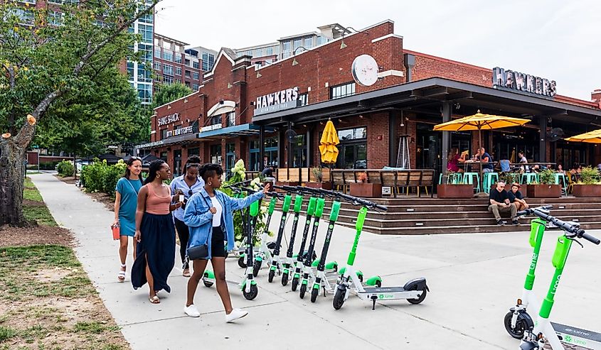Group of four young women walking to Hawkers Asian Street Fare restaurant in South End, with people dining at outside veranda.
