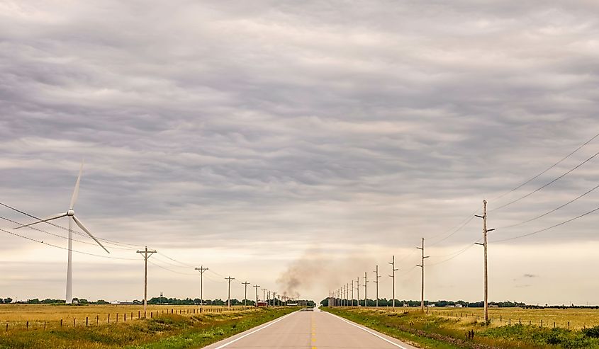 Perspective of Nebraska Highway 12, also known as Outlaw Trail Scenic Byway, with wind turbine (left), smoke rising from a house fire in the town of Springview, and mirage of water across pavement