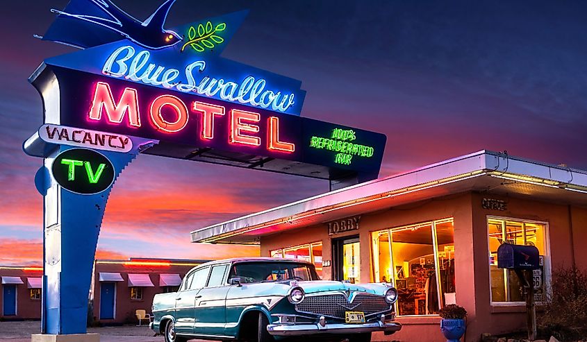 66 号公路上历史悠久的蓝燕汽车旅馆，日落时分霓虹灯和经典汽车。