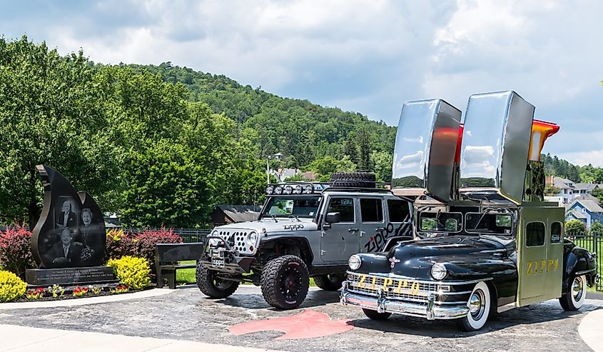 A car and a jeep parked outside of the Zippo Case Museum advertising the building along with a memorial to the founders of the business on a sunny summer day, Bradford, Pennsylvania.