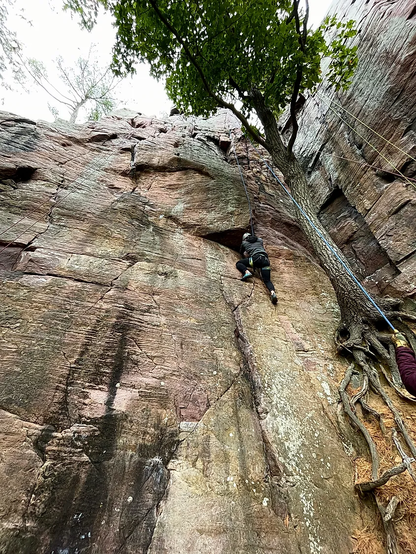 Men rock climbing with top rote technique in Devil's Lake State Park, Wisconsin.