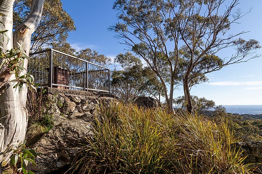 Camel’s Hump, a scenic viewpoint at the highest point of Mount Macedon, Victoria, Australia. Looking back to the small viewing platform, surrounded by eucalyptus trees and a suburb view. Alira Vale via Shutterstock