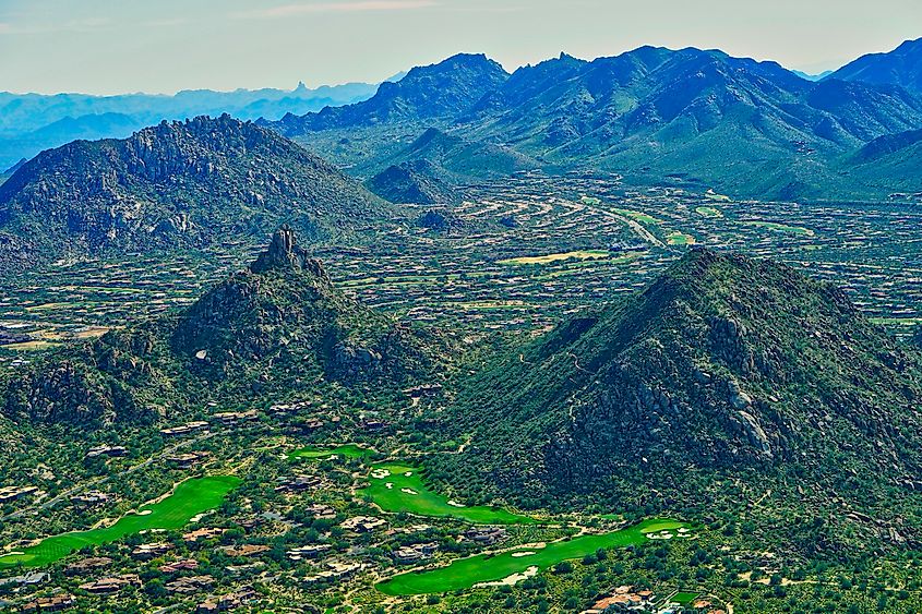 Aerial view of Pinnacle Peak, McDowell Sonoran Preserve, multiple Troon Golf course fairways, and overhead views of residential neighborhoods in Troon Village in Scottsdale, Arizona USA.