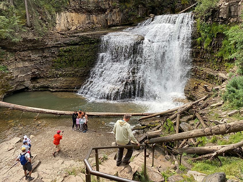 A small crown gathers at the base of a short, wide waterfall. 