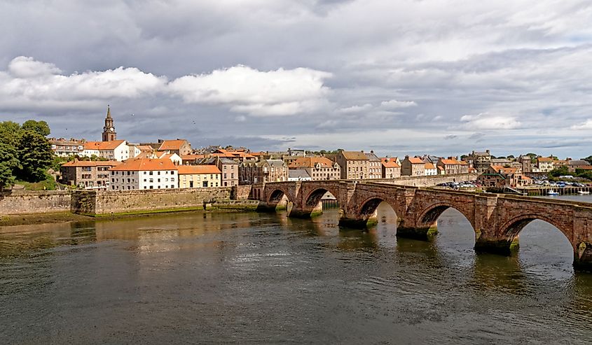 Historic stone bridge crossing River Tweed with dark grey clouds