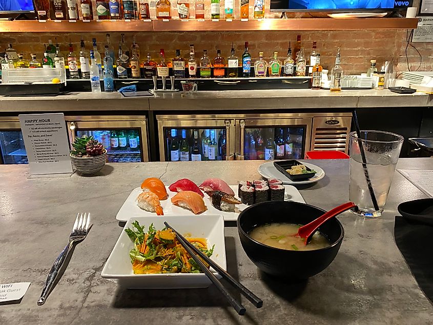 A bar top dinner of sushi, salad, and miso soup.