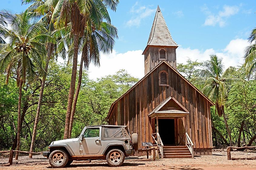 An old historic wooden church surrounded by palm trees on Lanai Island in Hawaii.