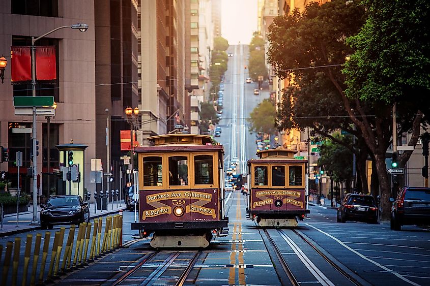 Classic view of historic traditional Cable Cars riding on famous California Street in morning light at sunrise with retro vintage style cross processing filter effect, San Francisco, California