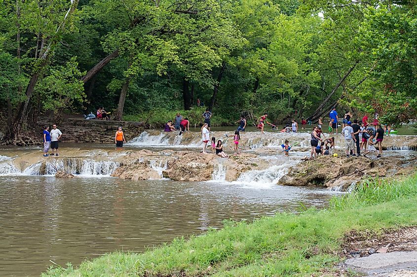 eople are swimming and playing in the water of Honey Creek near Turner Falls, Oklahoma.