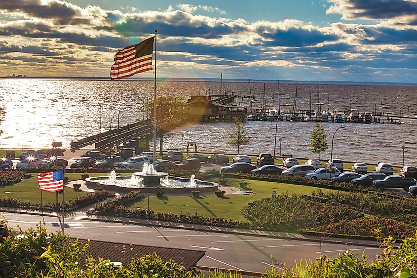 Aerial view of the coast in Fairhope, Alabama, featuring cars, boats, and American flags waving.