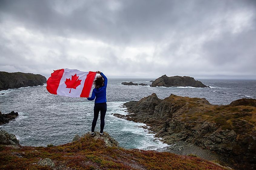 Adventurous woman holding a Canadian Flag, Newfoundland