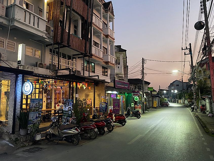 Scooters parked outside a hostel and cannabis dispensary. Evening descends