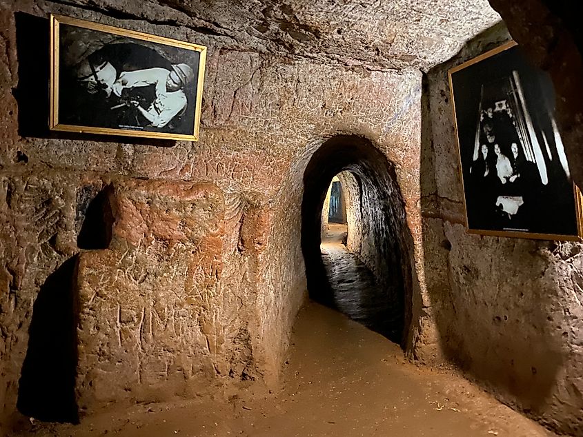 A small subterranean room with black and white photos leads to another tight tunnel.
