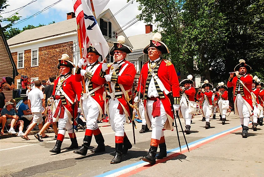 Adults dressed in British red coats from the American Revolution, march in a fourth of July parade in Bristol, Rhode island.