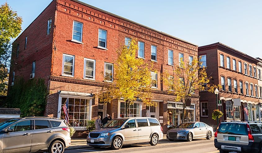 Traditional American brick buildings with shops along a busy street at sunset. Woodstock, VT, USA