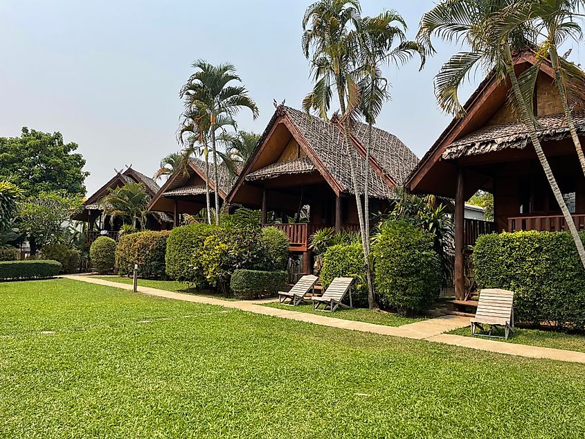 Thatched bungalows stand in a row before a well-groomed lawn.
