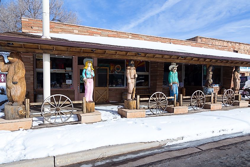 Wooden statues standing in front of an Indigenous-owned store along Route 66 in Williams, Arizona, with light winter snow on the ground